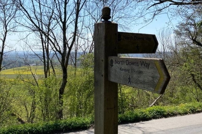 a sign on a wooden bench next to a tree