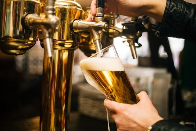 a person pouring a pint of beer in a pub