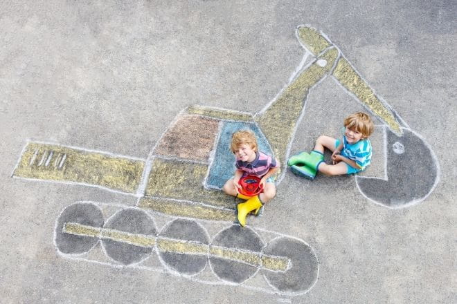 two children sat on a chalk drawing of a digger