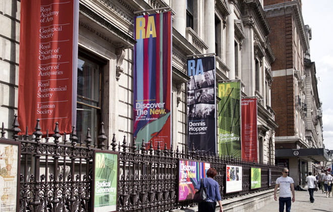 A group of people walking outside past an art gallery