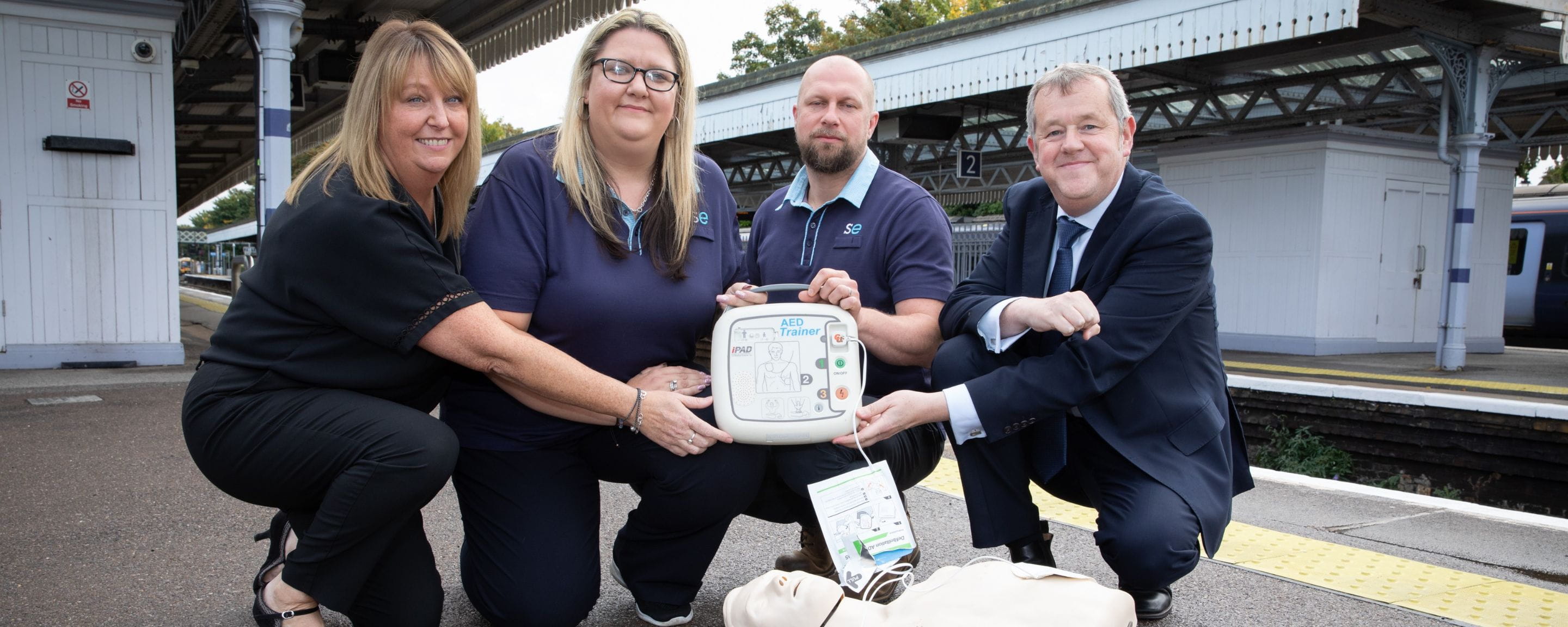 Southeastern staff at a station holding an AED defibrillator