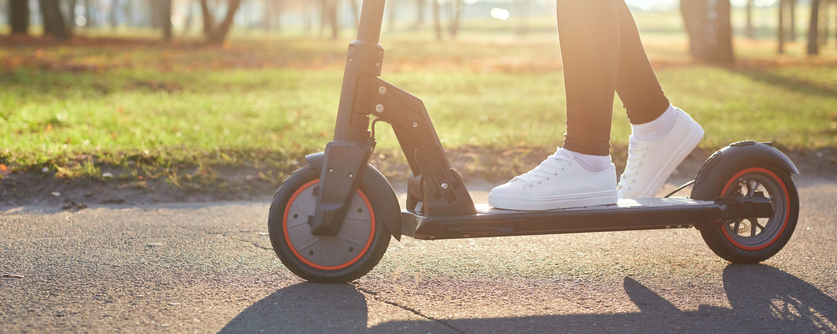 person with white trainers on a black e-scooter