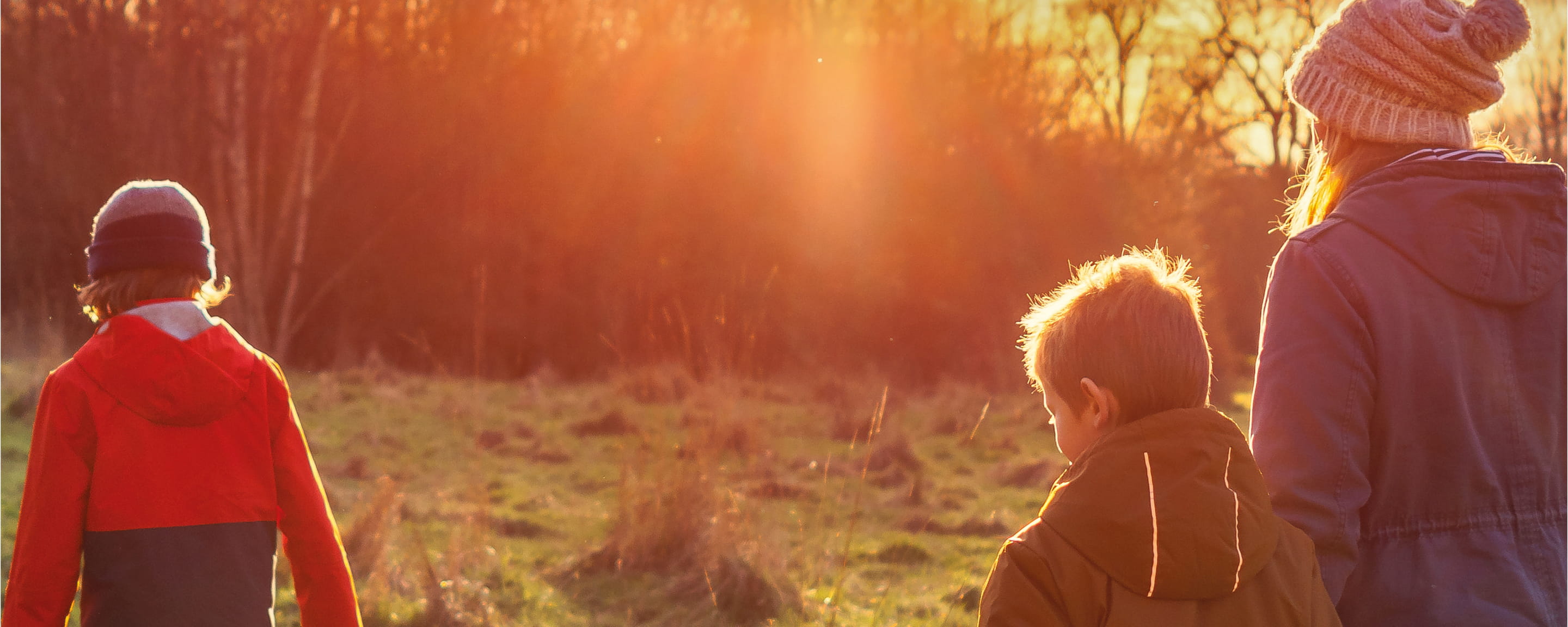 A mother and her children walking through a field in the Winter sun