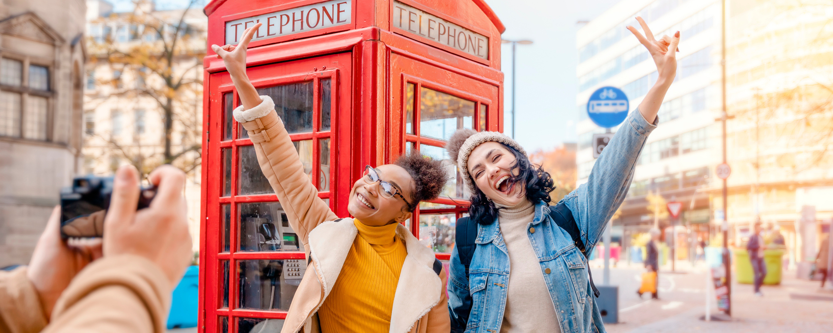 Two female friends pose outside a red telephone box in London