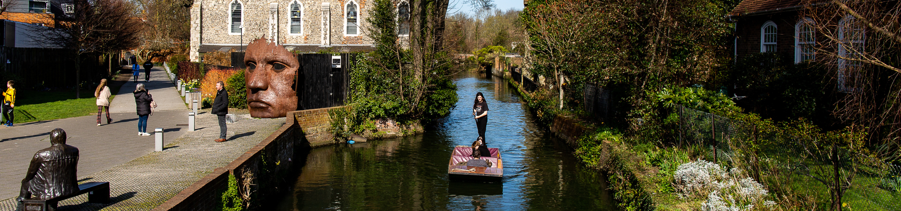 People punting down the river in Canterbury and walking on the riverbank