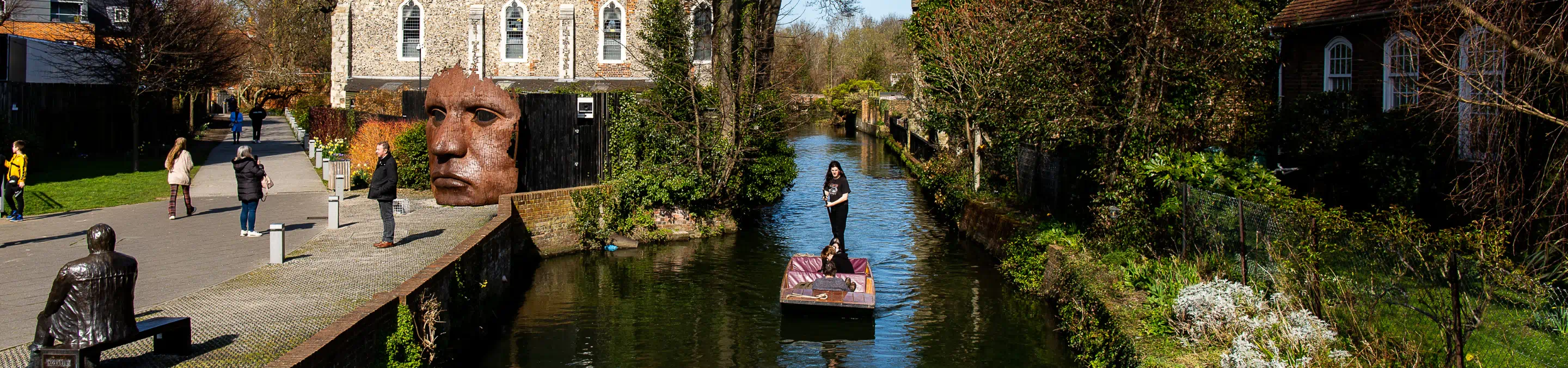 People punting down the river in Canterbury and walking on the riverbank