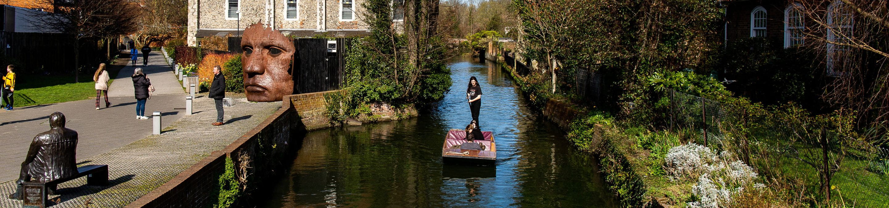 People punting down the river in Canterbury and walking on the riverbank