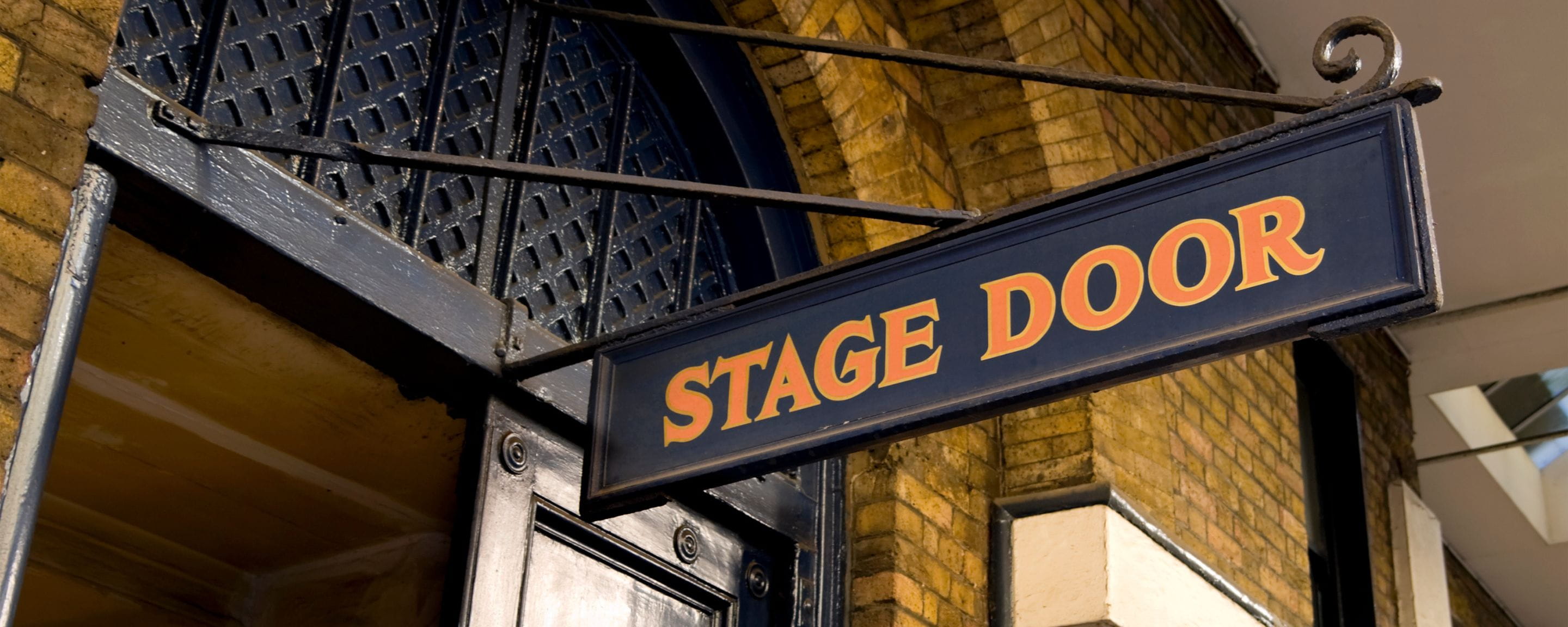 a stage door sign hanging from a theatre building