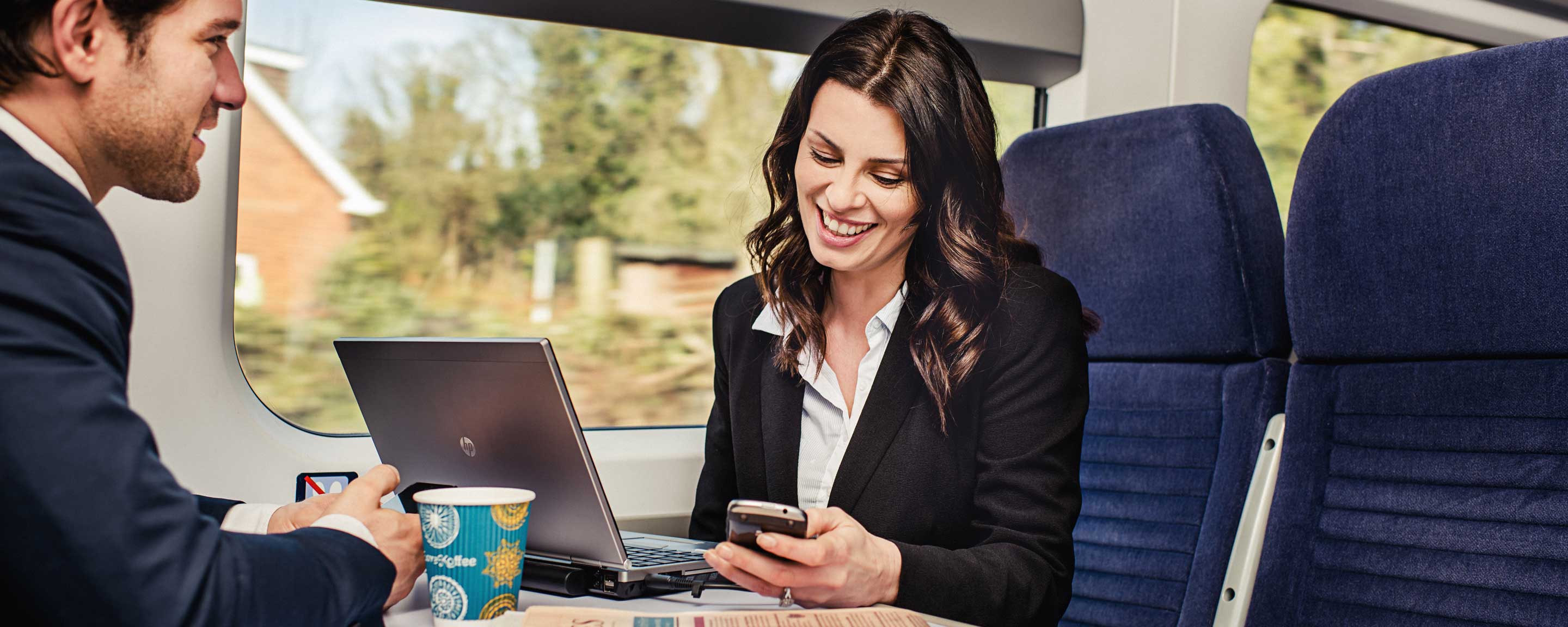 Business woman and man using phone on train