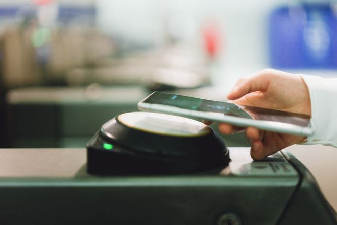 woman using digital ticket on phone to tap in at a station