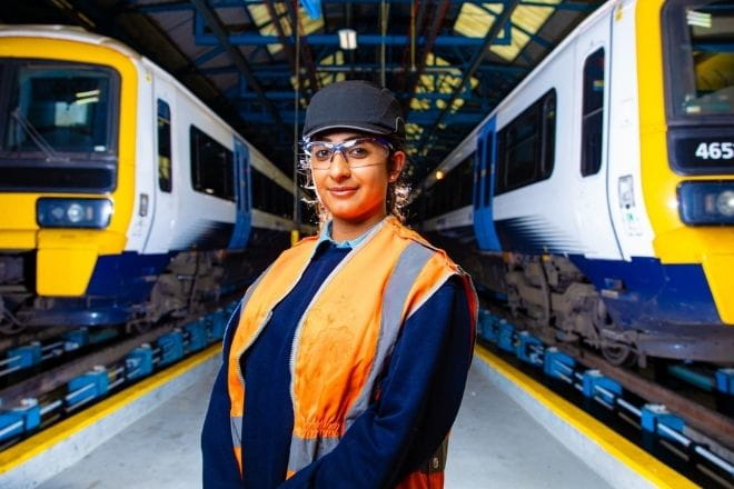 a young woman standing next to two trains on a platform