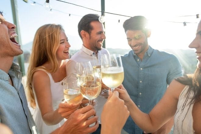 a group of people laughing and drinking wine