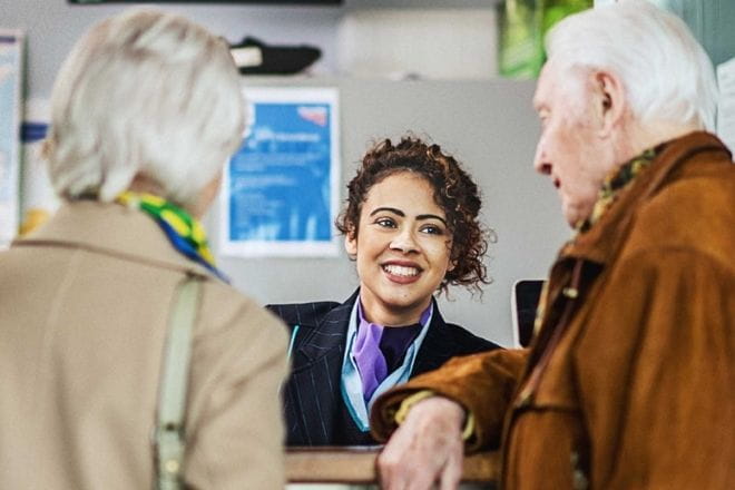 two older people taking to a woman behind a desk