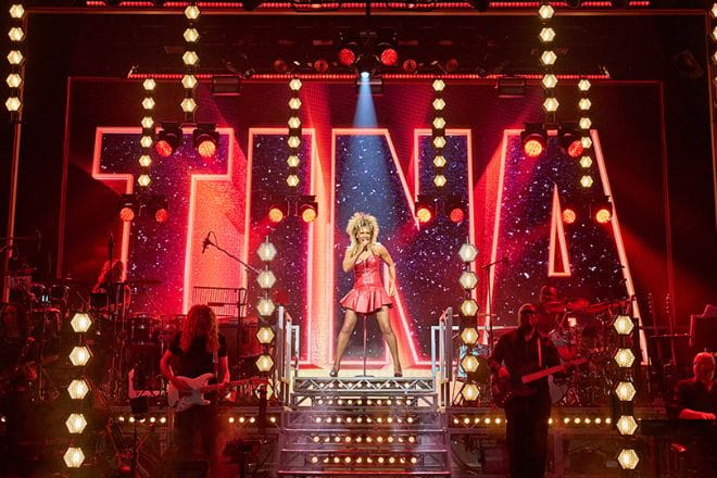 Stage with actress playing Tina Turner on a stage with giant letters spelling Tina in the background