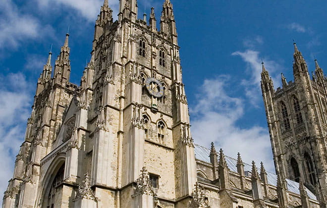 a large tall tower with a clock on the side of Canterbury Cathedral