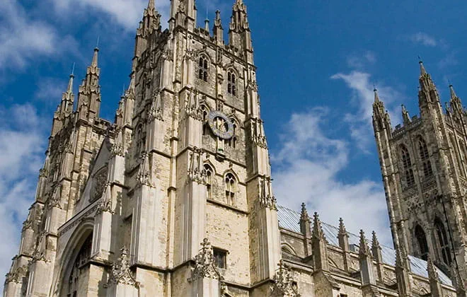 a large tall tower with a clock on the side of Canterbury Cathedral