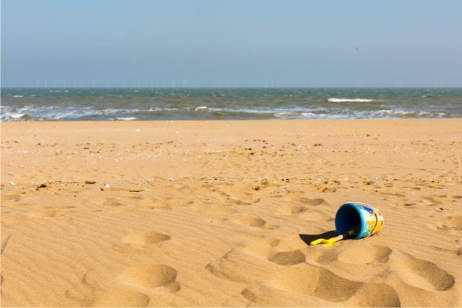 Sandy beach with a bucket and spade and the sea in the distance